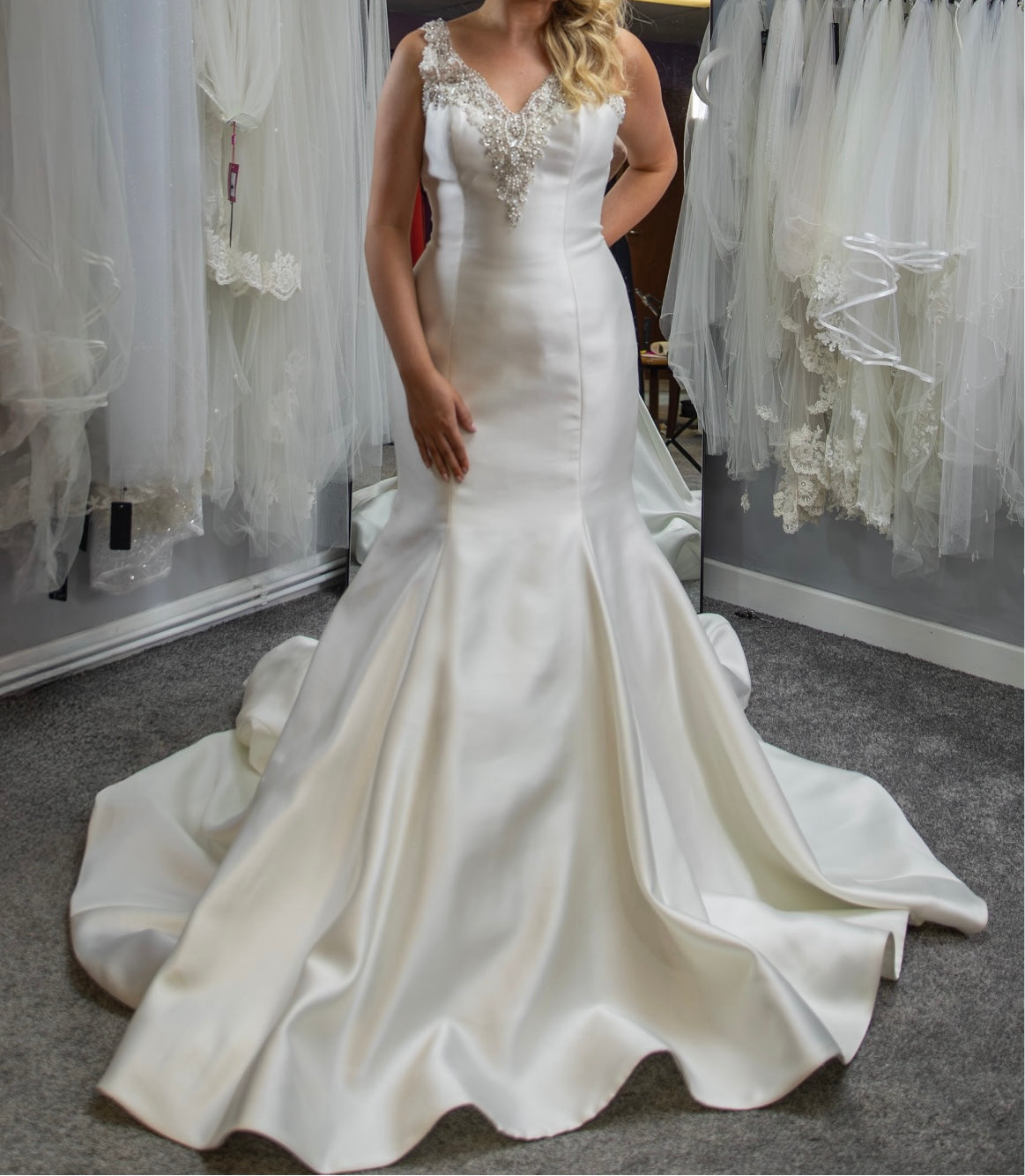 White wedding dress with intricate detailing in a fitting room setting