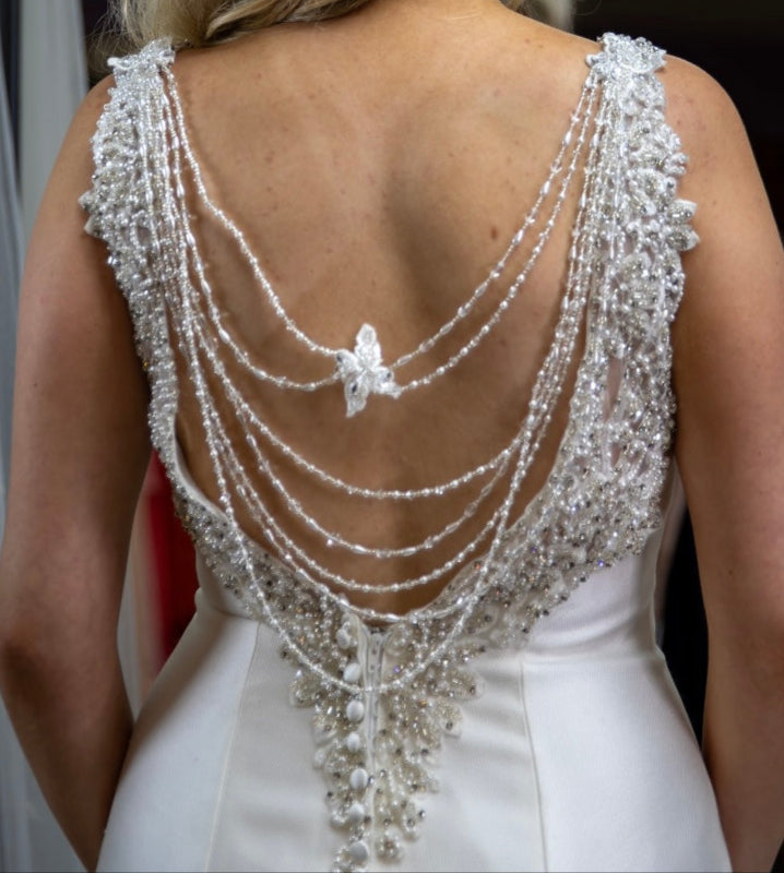 Close-up of a white dress with intricate beaded back design.